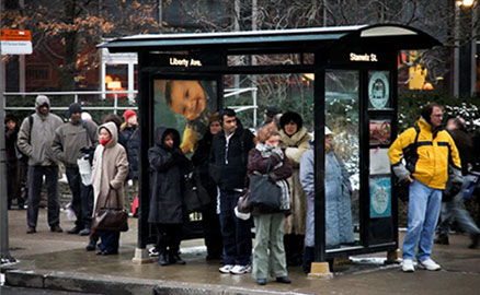 People waiting for a bus at a Downtown bus shelter on a cold winter day.
